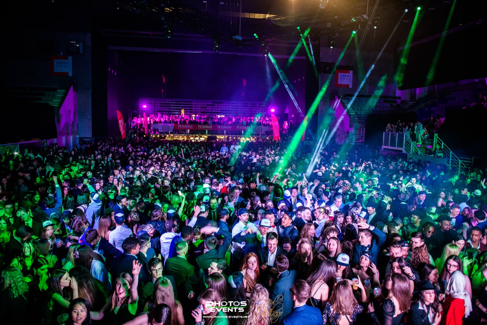 A packed dance floor under green lasers